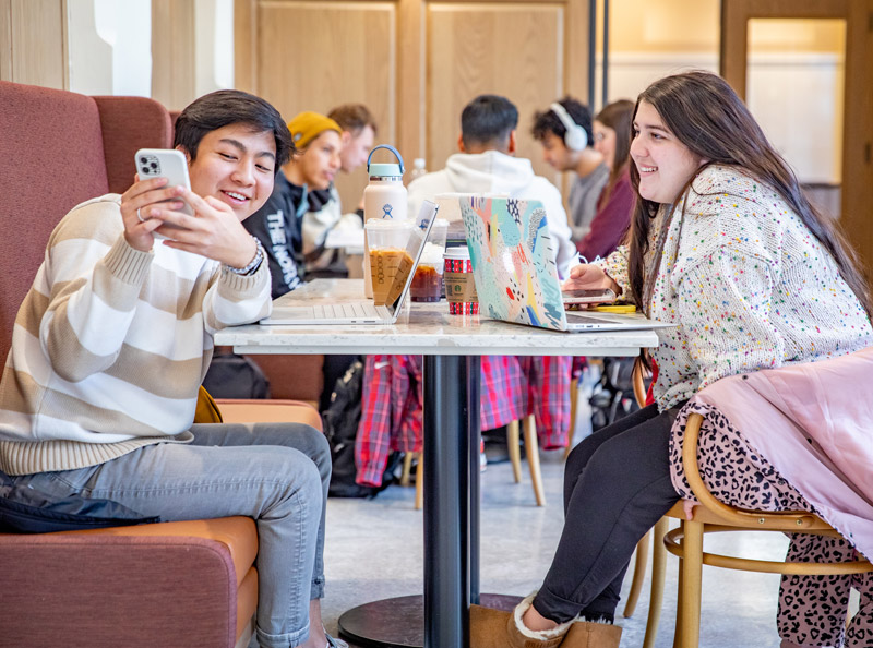 Students sitting at a table with their phones