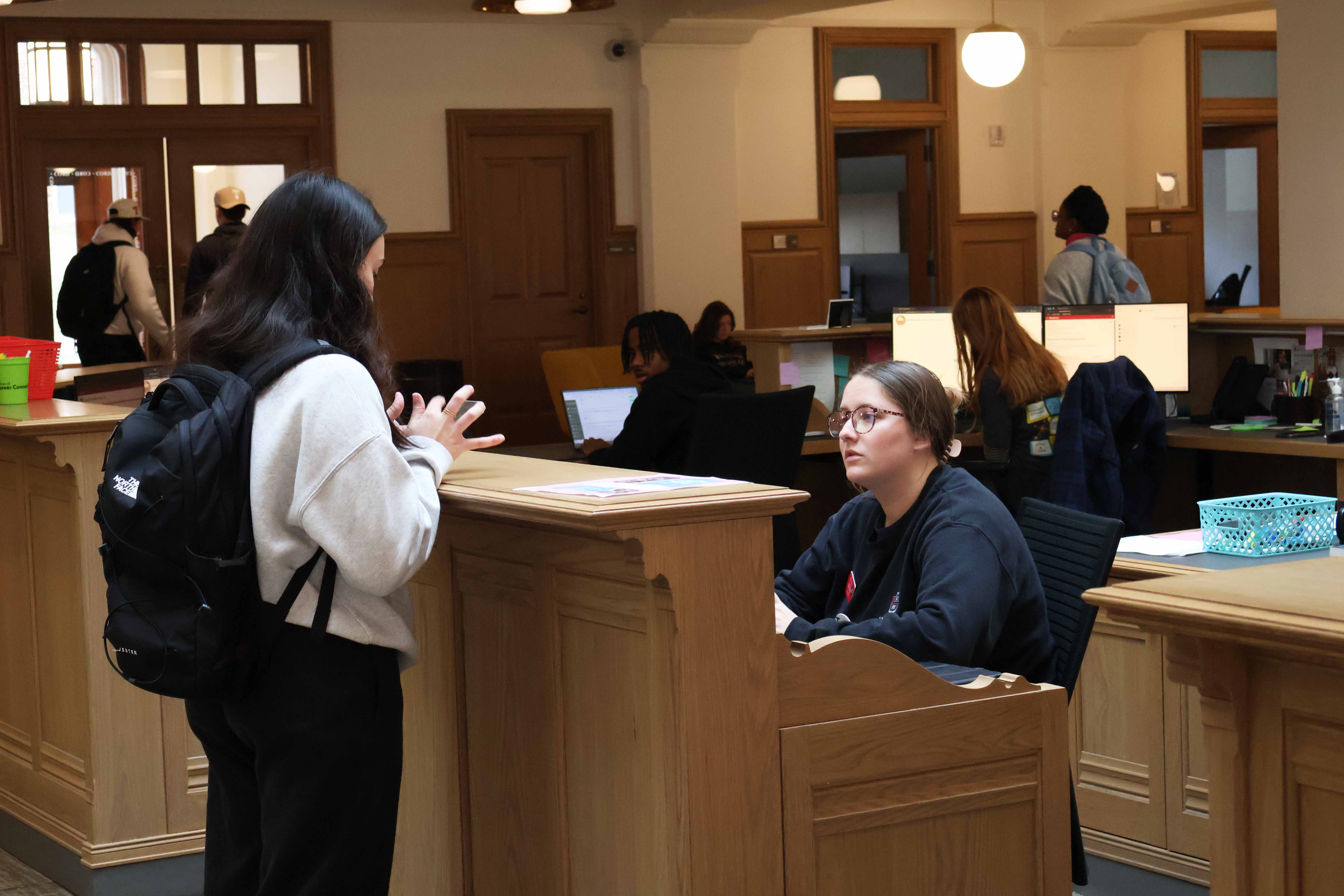 A student guide assists someone at the welcome desk